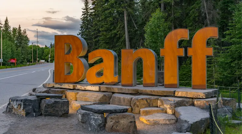 The wooden Banff sign at the entrance to the town of Banff at dusk