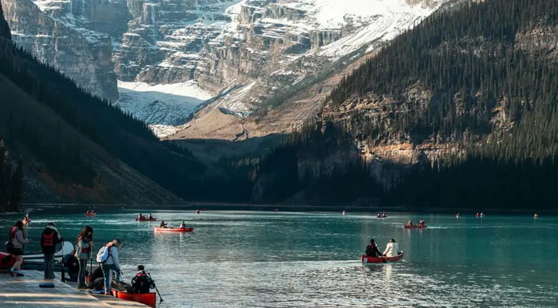 Red canoes on the turquoise water of Lake Louise below the Victoria Glacier