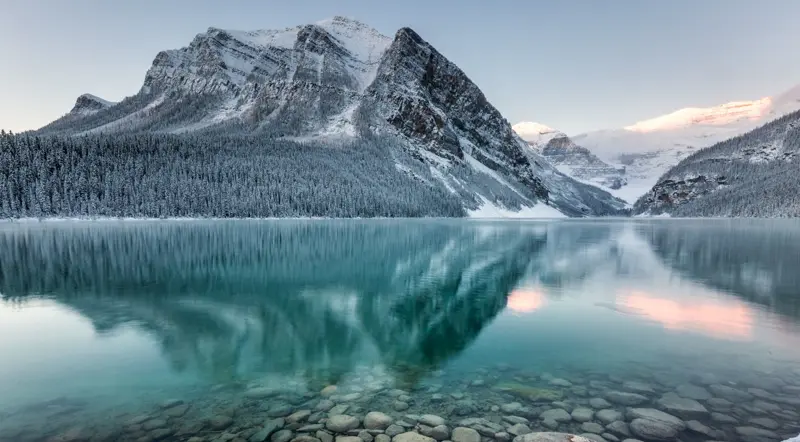 Snowy mountains reflected in the clear winter water of Lake Louise