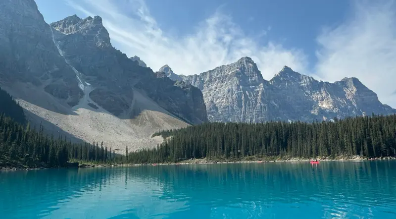 Vivid turquoise water of Moraine Lake seen from the shoreline on a clear day